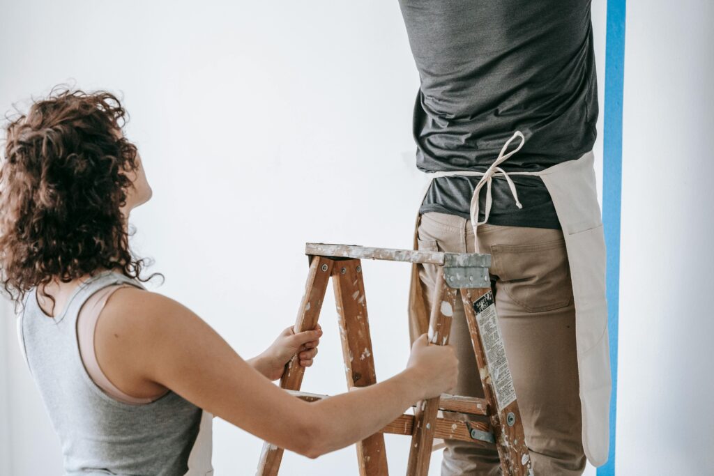 Couple working together to paint a wall during home renovation, featuring teamwork and DIY spirit.